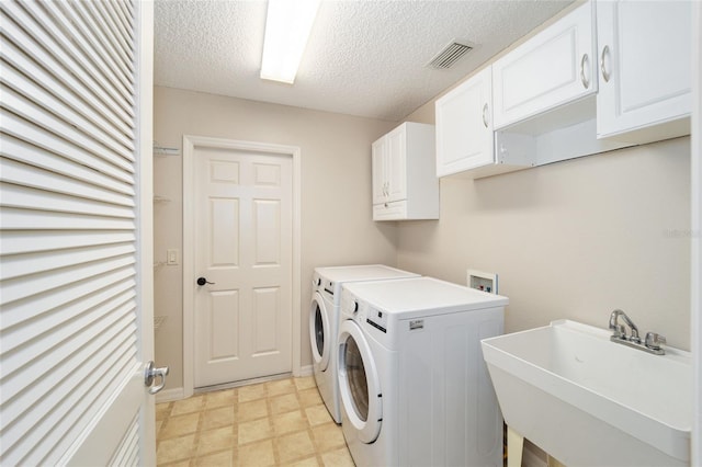 laundry room with sink, independent washer and dryer, a textured ceiling, and cabinets