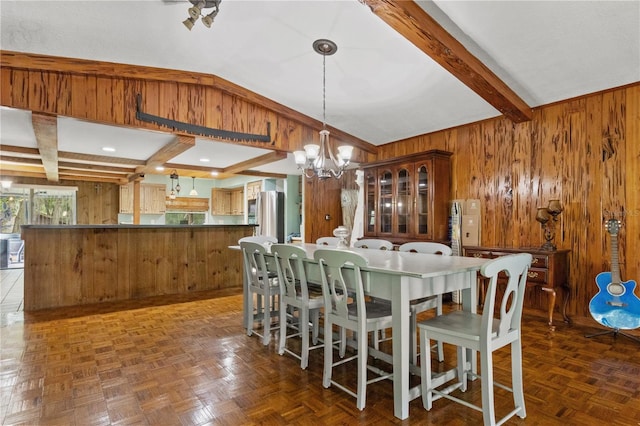 dining space featuring wood walls, dark parquet floors, a notable chandelier, and vaulted ceiling with beams