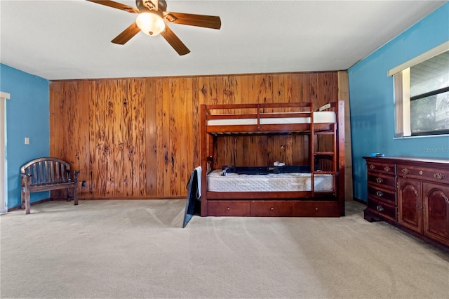 unfurnished bedroom featuring light colored carpet, ceiling fan, and wood walls