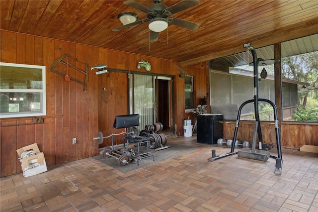 exercise area featuring ceiling fan, wooden walls, and wooden ceiling