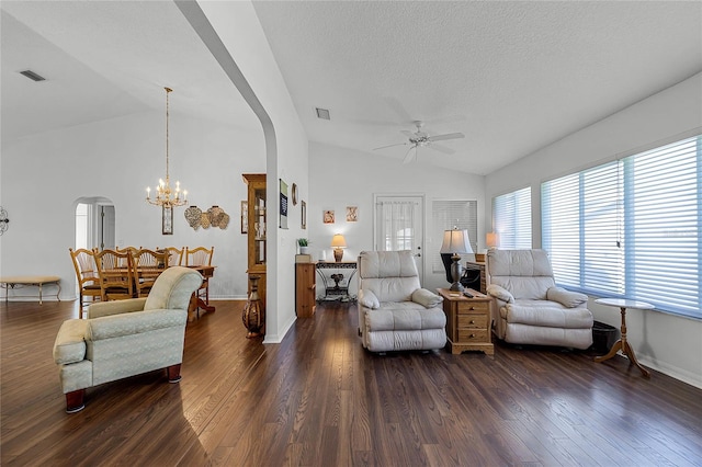 living room with lofted ceiling, dark wood-type flooring, and ceiling fan with notable chandelier