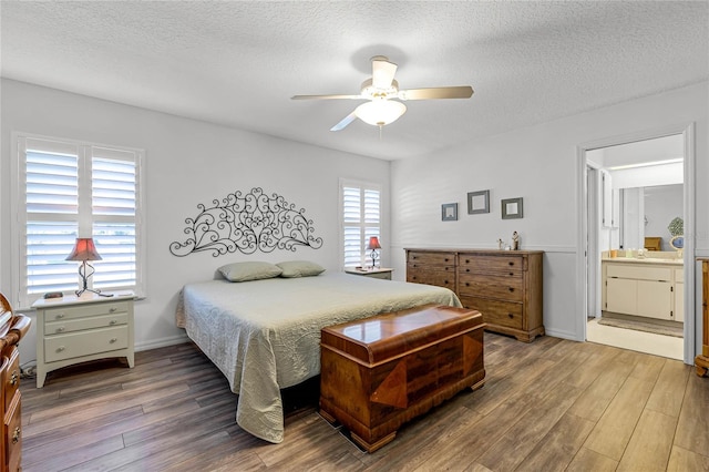 bedroom featuring a textured ceiling, ceiling fan, wood-type flooring, and connected bathroom