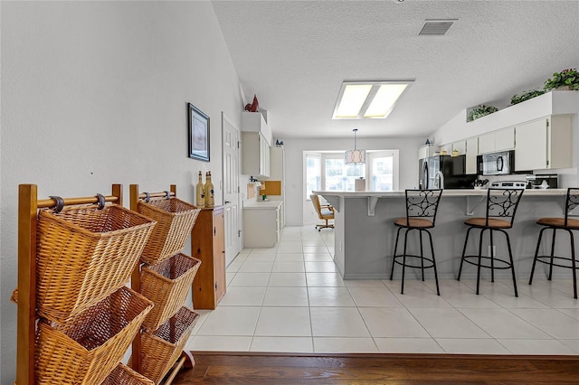 kitchen featuring white cabinetry, a kitchen bar, kitchen peninsula, and decorative light fixtures