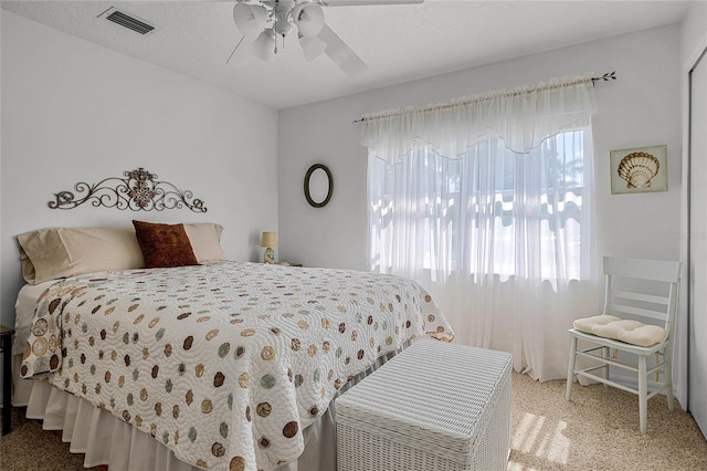 bedroom with a textured ceiling, ceiling fan, and light carpet