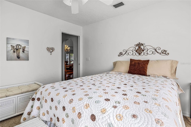 bedroom with a ceiling fan, visible vents, and a textured ceiling