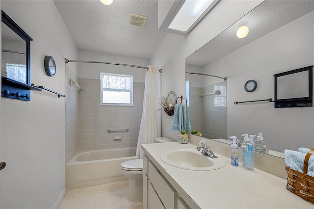 full bathroom featuring a skylight, toilet, shower / bath combination with curtain, vanity, and a textured ceiling