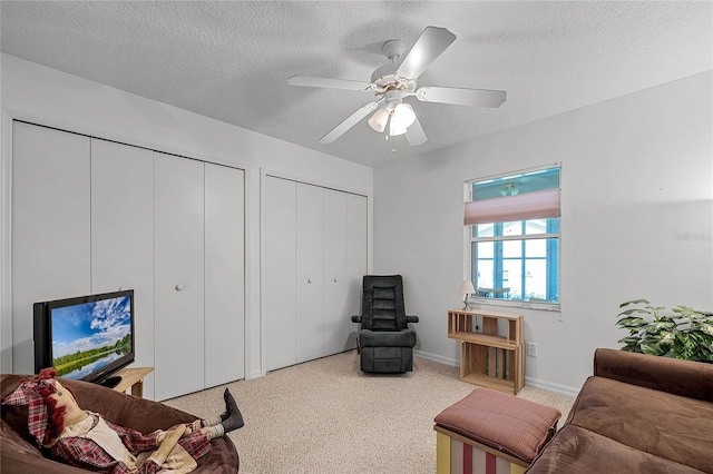 carpeted living room with ceiling fan and a textured ceiling