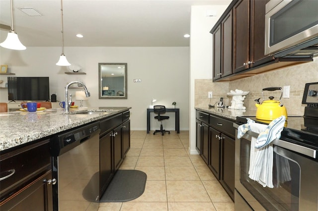 kitchen with decorative light fixtures, light tile patterned floors, stainless steel appliances, sink, and light stone counters