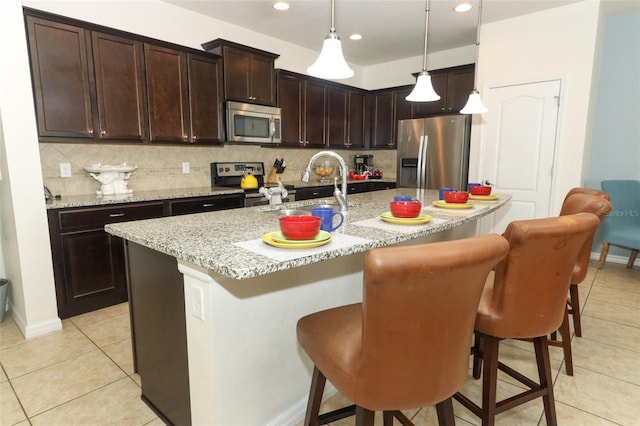 kitchen with appliances with stainless steel finishes, a center island with sink, sink, and pendant lighting