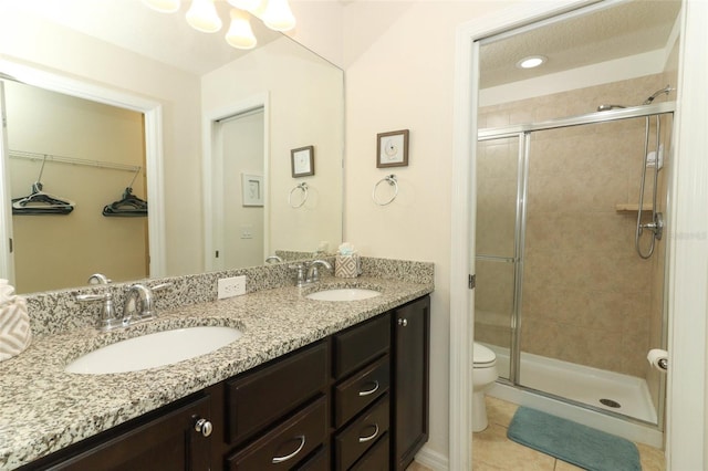 bathroom with tile patterned flooring, vanity, toilet, and a shower with shower door