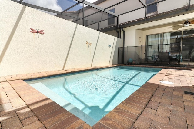 view of pool with glass enclosure, a patio area, and ceiling fan