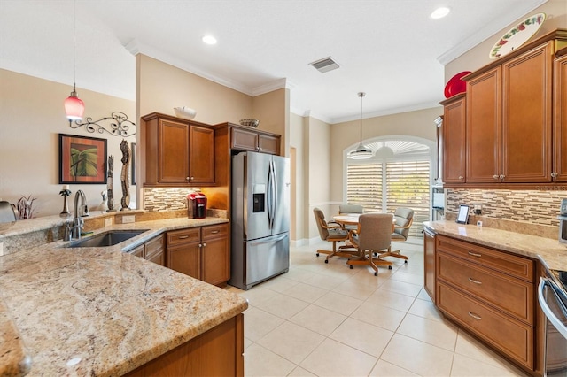 kitchen with stainless steel fridge, decorative light fixtures, light stone counters, and sink