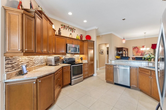 kitchen featuring an inviting chandelier, ornamental molding, tasteful backsplash, decorative light fixtures, and stainless steel appliances