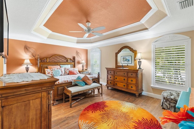 bedroom featuring a raised ceiling, ceiling fan, and light hardwood / wood-style floors