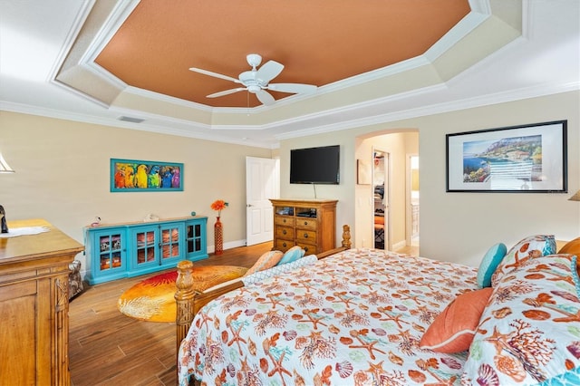 bedroom featuring a tray ceiling, ceiling fan, crown molding, and hardwood / wood-style flooring