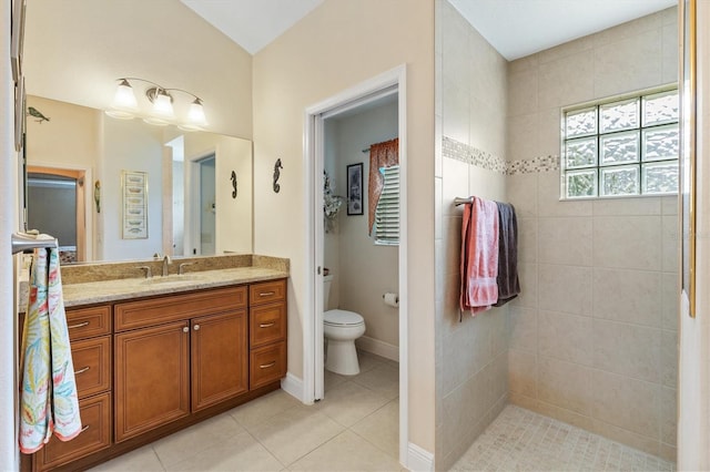 bathroom featuring tile patterned floors, vanity, a tile shower, and toilet