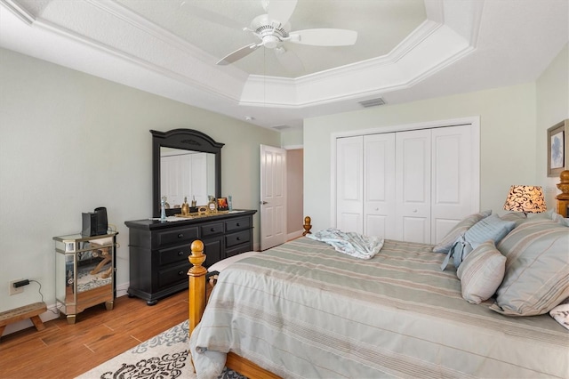 bedroom with a tray ceiling, ceiling fan, a closet, and crown molding