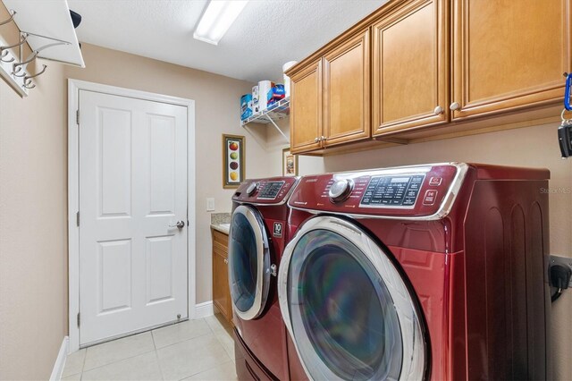 clothes washing area featuring washer and clothes dryer, light tile patterned flooring, and cabinets