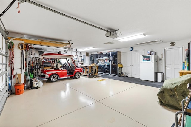 garage with a workshop area, a garage door opener, and white refrigerator