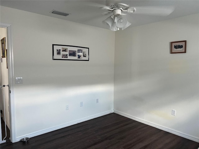 unfurnished room with dark wood-style floors, visible vents, baseboards, and a ceiling fan