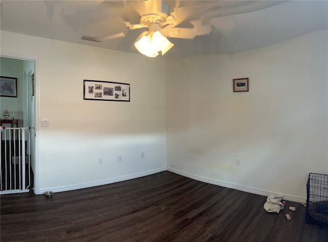 spare room featuring visible vents, dark wood-style flooring, a ceiling fan, and baseboards