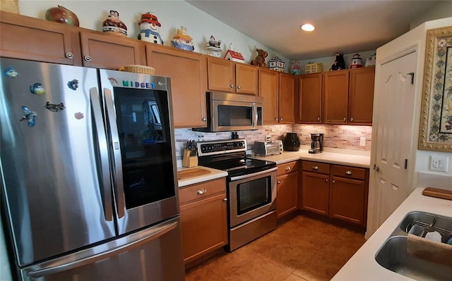 kitchen featuring appliances with stainless steel finishes, light countertops, a sink, and decorative backsplash