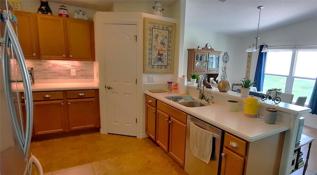 kitchen with a peninsula, appliances with stainless steel finishes, light countertops, and a sink