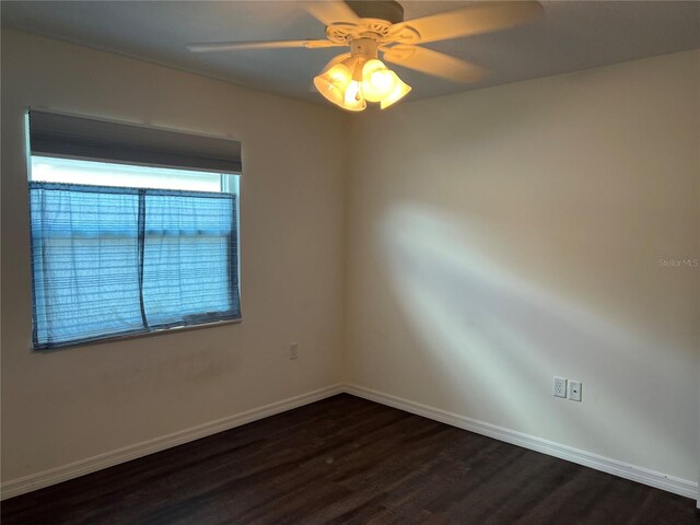 empty room featuring dark wood-type flooring, baseboards, and a ceiling fan