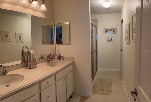 full bath with double vanity, a shower stall, a sink, and tile patterned floors