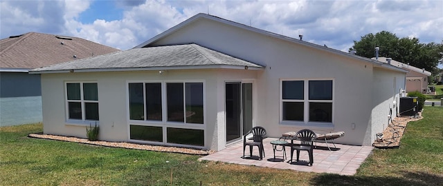 back of property with central air condition unit, a yard, roof with shingles, and a patio