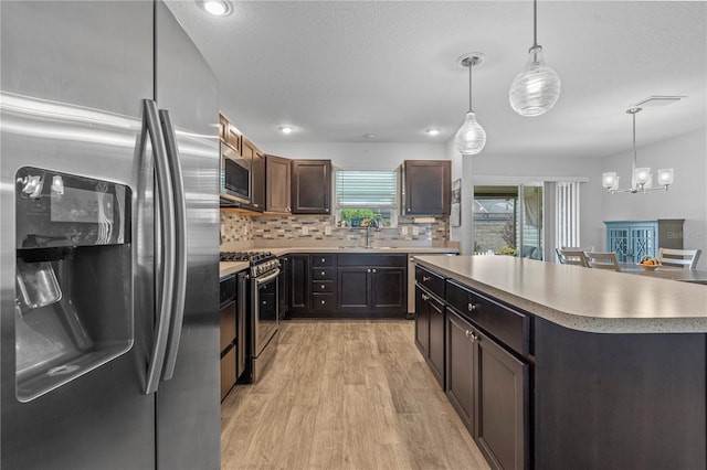 kitchen with a center island, stainless steel appliances, light hardwood / wood-style floors, pendant lighting, and decorative backsplash