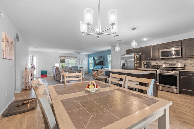 dining area with light wood-type flooring and ceiling fan with notable chandelier