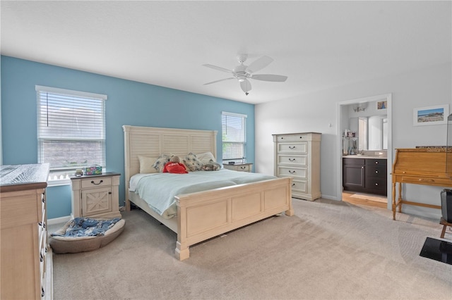 bedroom featuring ceiling fan, sink, light carpet, and ensuite bath