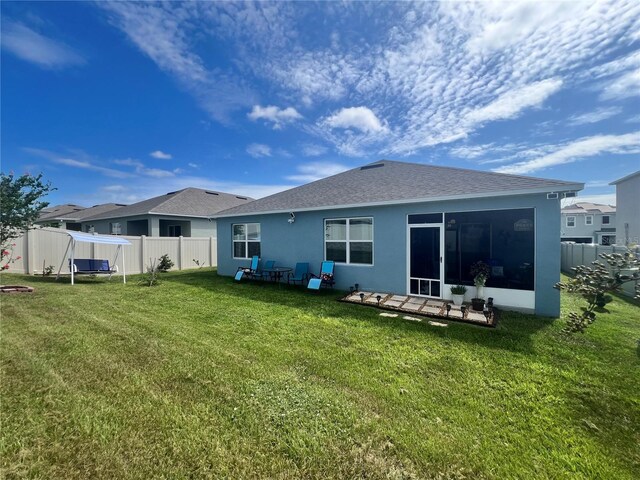 back of property featuring a sunroom and a yard