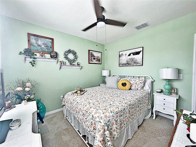 carpeted bedroom featuring ceiling fan and a textured ceiling