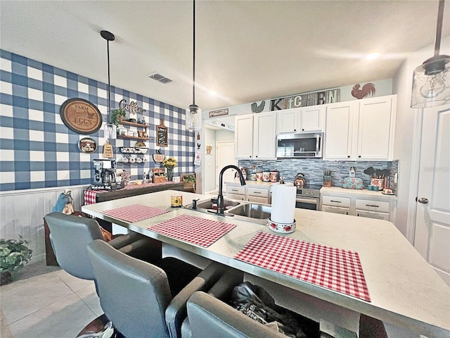 kitchen featuring sink, white cabinets, decorative light fixtures, and appliances with stainless steel finishes