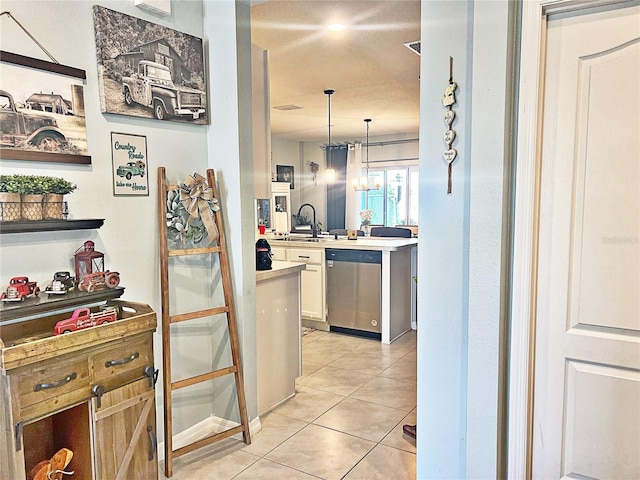 kitchen with sink, pendant lighting, dishwasher, white cabinetry, and light tile patterned flooring