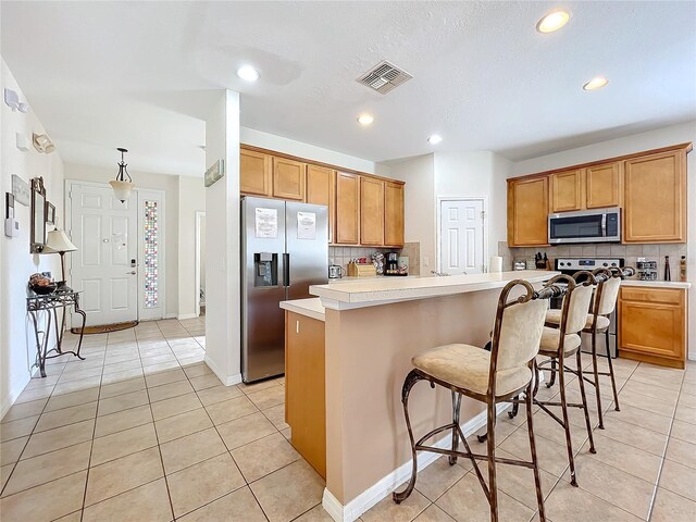 kitchen with a kitchen island, a breakfast bar, stainless steel appliances, and tasteful backsplash