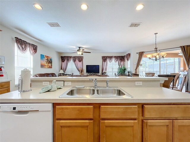 kitchen featuring a kitchen island with sink, pendant lighting, ceiling fan with notable chandelier, dishwasher, and sink