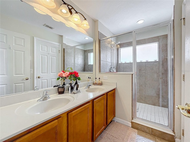 bathroom featuring a shower with door, vanity, tile patterned flooring, and a textured ceiling