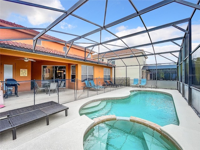 view of pool with glass enclosure, ceiling fan, and a patio area