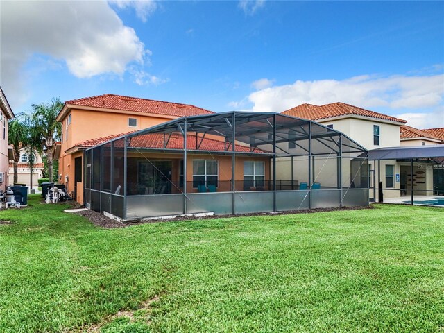 rear view of property featuring a patio area, a swimming pool, a yard, and a lanai