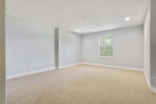 spare room featuring recessed lighting, baseboards, a textured ceiling, and light colored carpet