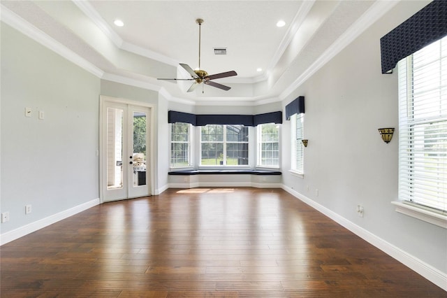 unfurnished room with a tray ceiling, visible vents, wood finished floors, and ornamental molding