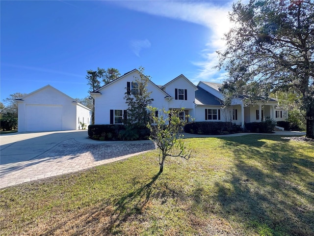 view of front of house featuring a garage, an outdoor structure, and a front lawn