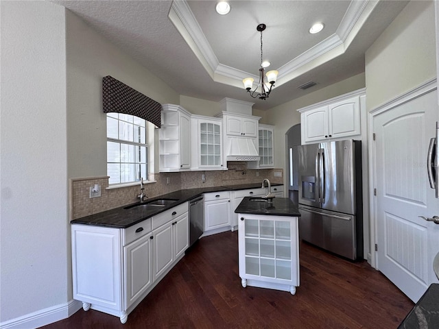 kitchen featuring a tray ceiling, dark wood-style flooring, tasteful backsplash, appliances with stainless steel finishes, and a sink