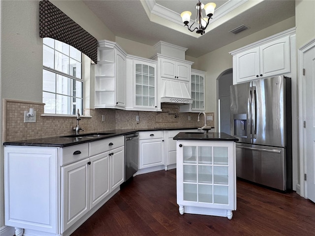 kitchen with custom exhaust hood, stainless steel appliances, dark countertops, a raised ceiling, and visible vents