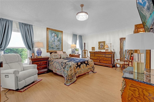 bedroom with crown molding, a textured ceiling, a notable chandelier, and light hardwood / wood-style flooring