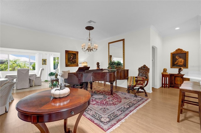 living room featuring ornamental molding, a notable chandelier, and light hardwood / wood-style floors