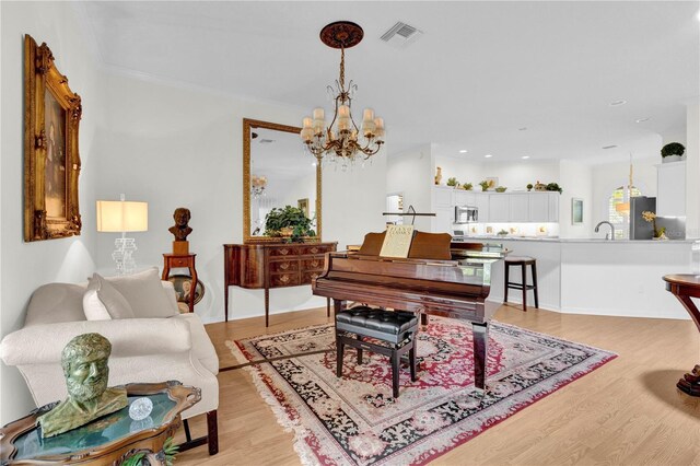 interior space featuring crown molding, sink, a notable chandelier, and light hardwood / wood-style floors